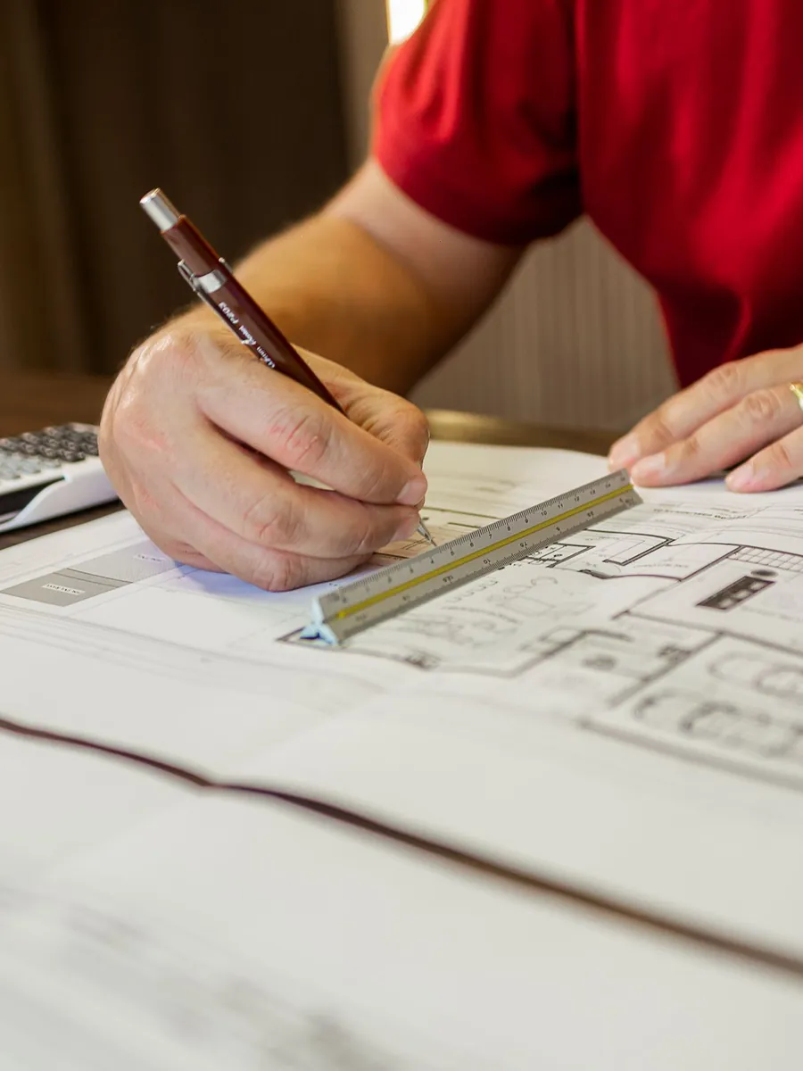 Hands drawing a floor plan with a ruler